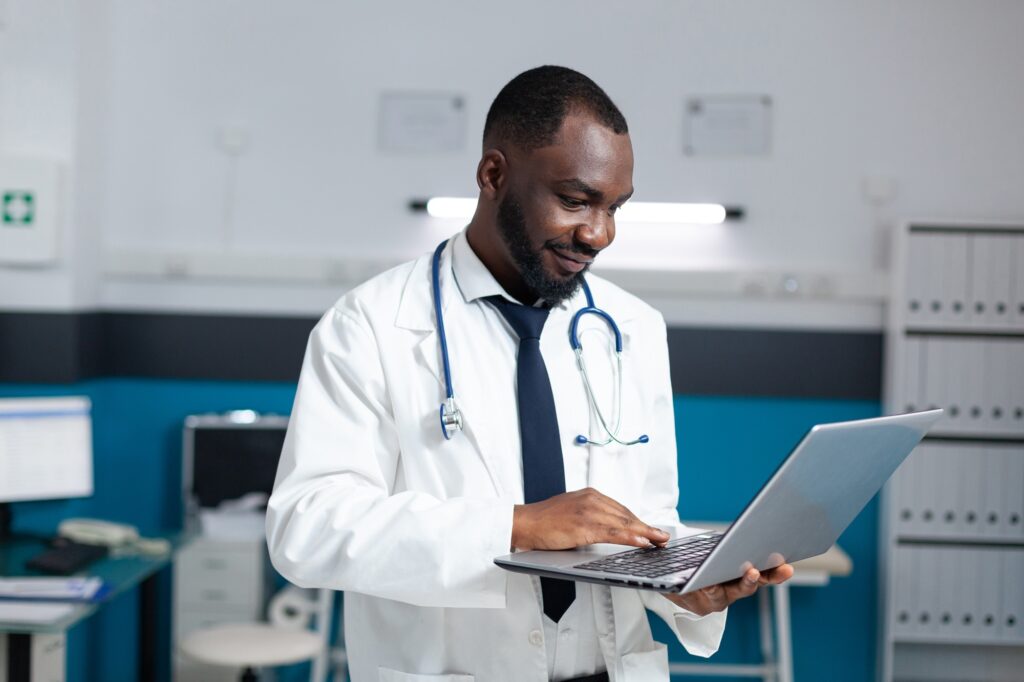 African american therapist doctor holding laptop computer looking at online medicine prescription